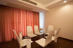 A conference room with a glass table and white chairs, a red curtain, and a white wall. - 4D - 3 Bedroom Downtown Apartment With Shared Pool (Bangkok)
