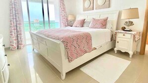 Un dormitorio con cama, mesita de noche, ventilador de techo y vistas al exterior.