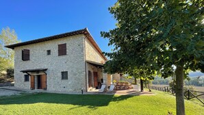 Ein Steinhhaus mit Terrasse und Sitzgelegenheit im Freien.
