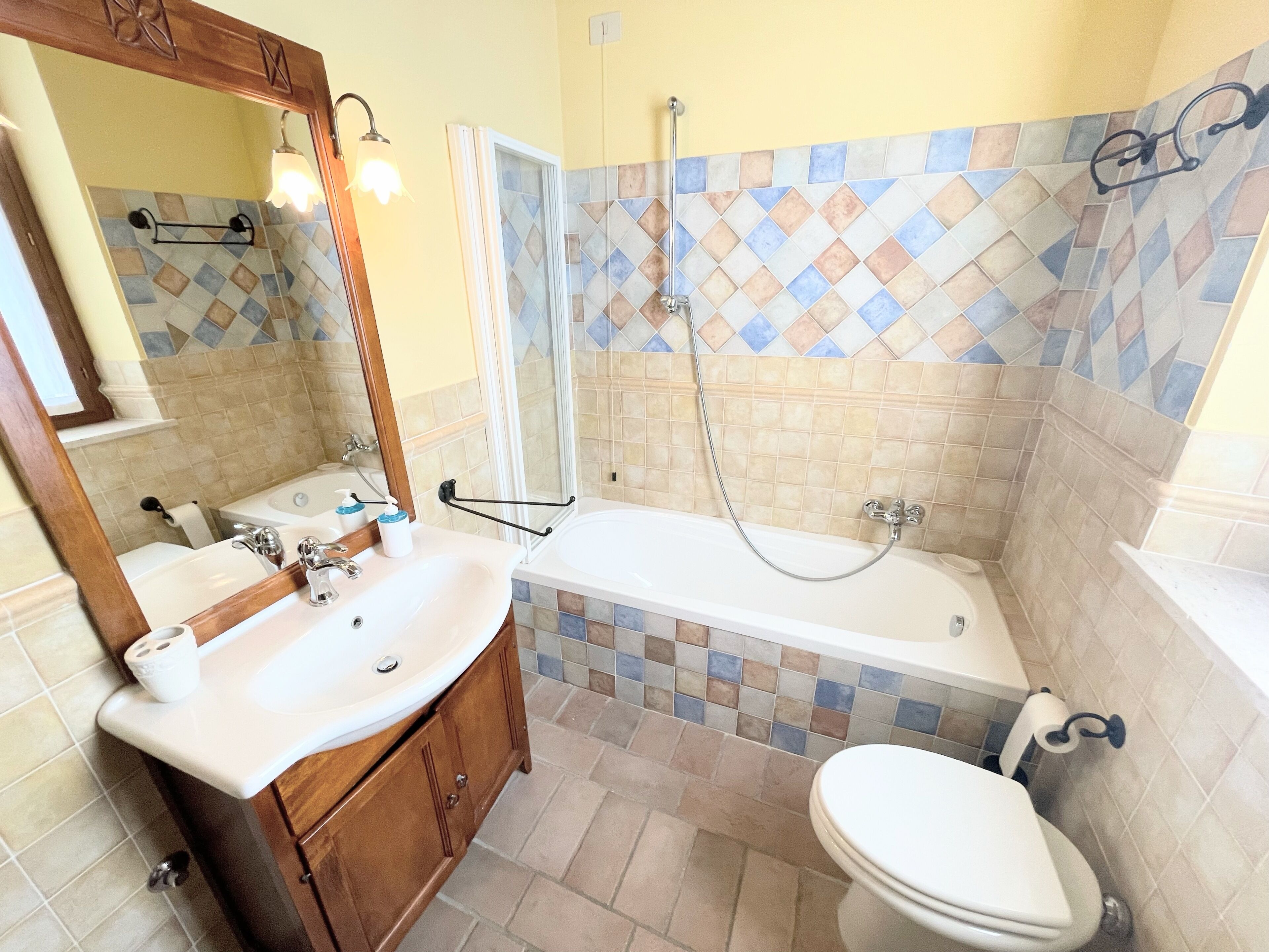 Ein Badezimmer mit Waschbecken, Spiegel, Waschtisch, Badewanne und Toilette.