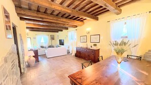 A spacious living area with a wooden ceiling, a dining table with chairs, a sofa set, and a fireplace. - Detached Villa - Sleeps 10 - Pool - Pergola - Playground for Children - Wifi (Todi)