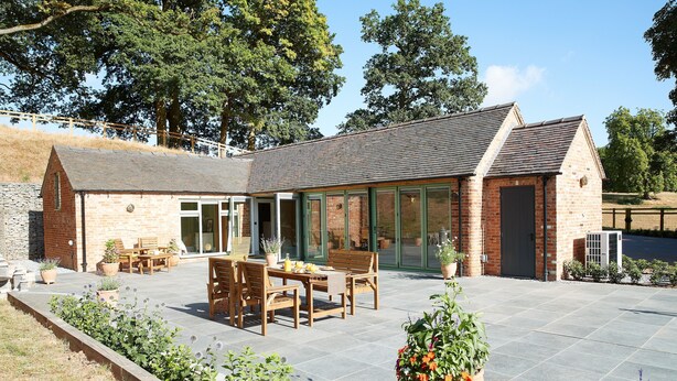 A brick building with a patio area, a dining table, and chairs.