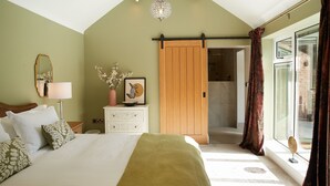 A bedroom with a large bed, a nightstand, a dresser, a mirror, a sliding door, and a view of the outside.