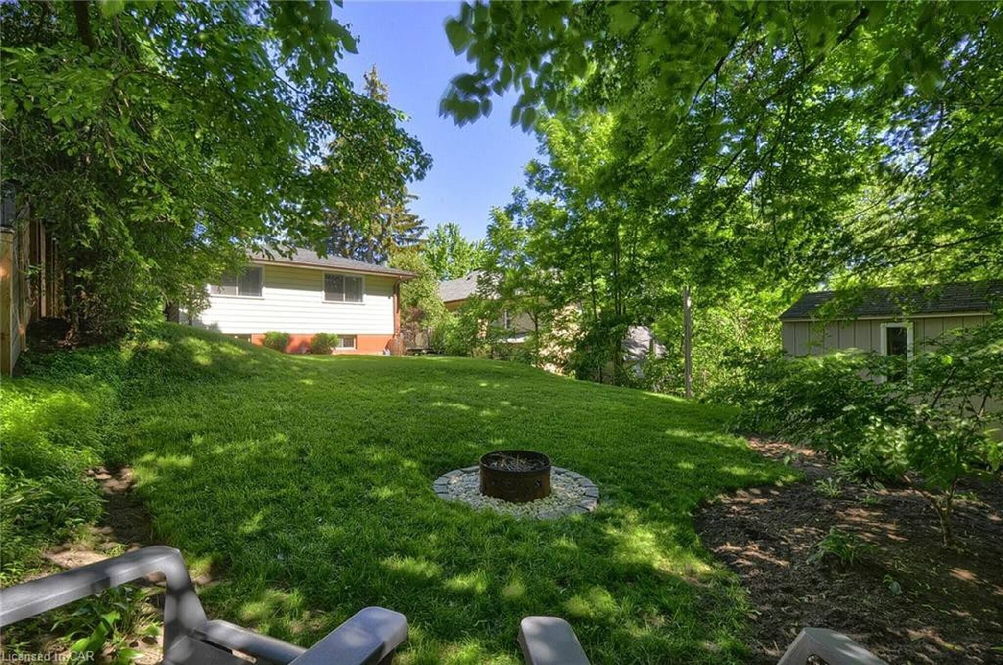 Un jardin avec un foyer extérieur, une pelouse et une maison.
