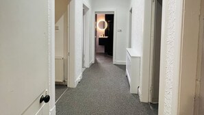A hallway with white walls and a grey carpet. There are doors on both sides leading to other rooms. - Luxury 3 Bedrooms Entire Flat - Self Check in & Check out (Cowdenbeath)