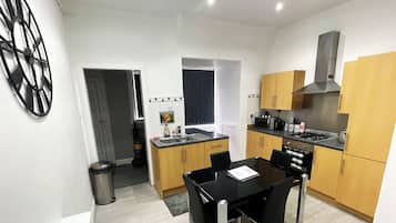 A modern kitchen with wooden cabinets, a black dining table, and a stainless steel sink.