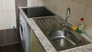 Eine kompakte Küche mit Einbauwaschmaschine, Edelstahlspüle und Arbeitsplatte.