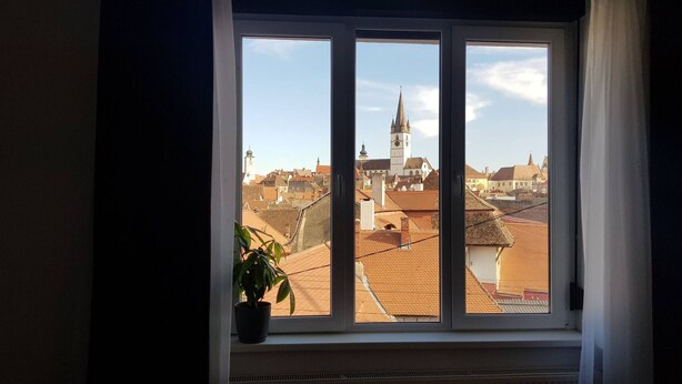 Ein Fenster mit Blick auf eine Stadt, darunter eine Kirche mit einem Glockenturm.