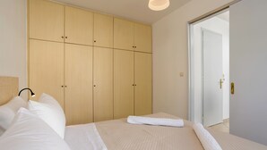 Ein Schlafzimmer mit Bett, Kleiderschrank und einer Tür zu einem weiteren Raum.