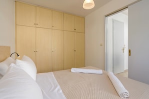 A bedroom with a bed, a wardrobe, and a door leading to another room. - Icabaru Private House With Garden & Bbq, Near Laganas, Zakynthos (Zakynthos)