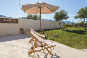 A lounge chair under an umbrella, a sign reading 'Icabariu,' and a potted plant. - Icabaru Private House With Garden & Bbq, Near Laganas, Zakynthos (Zakynthos)