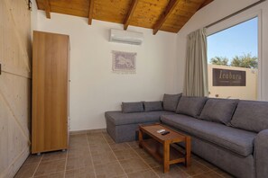 A living room with a grey sofa, a wooden cabinet, a small wooden table, and a sign reading 'Icabariu' on the wall. - Icabaru Private House With Garden & Bbq, Near Laganas, Zakynthos (Zakynthos)