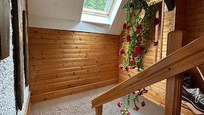 A wooden interior with a skylight, a hanging flower arrangement, and a wooden staircase. - Apartma Pohar- A Bit Different! (Bovec)