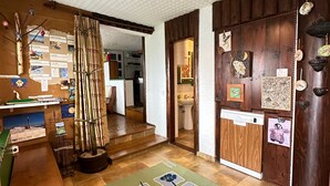 A cozy room with a wooden floor, a green and blue patterned rug, a hanging light fixture, and a bulletin board with various items pinned to it. - Apartma Pohar- A Bit Different! (Bovec)