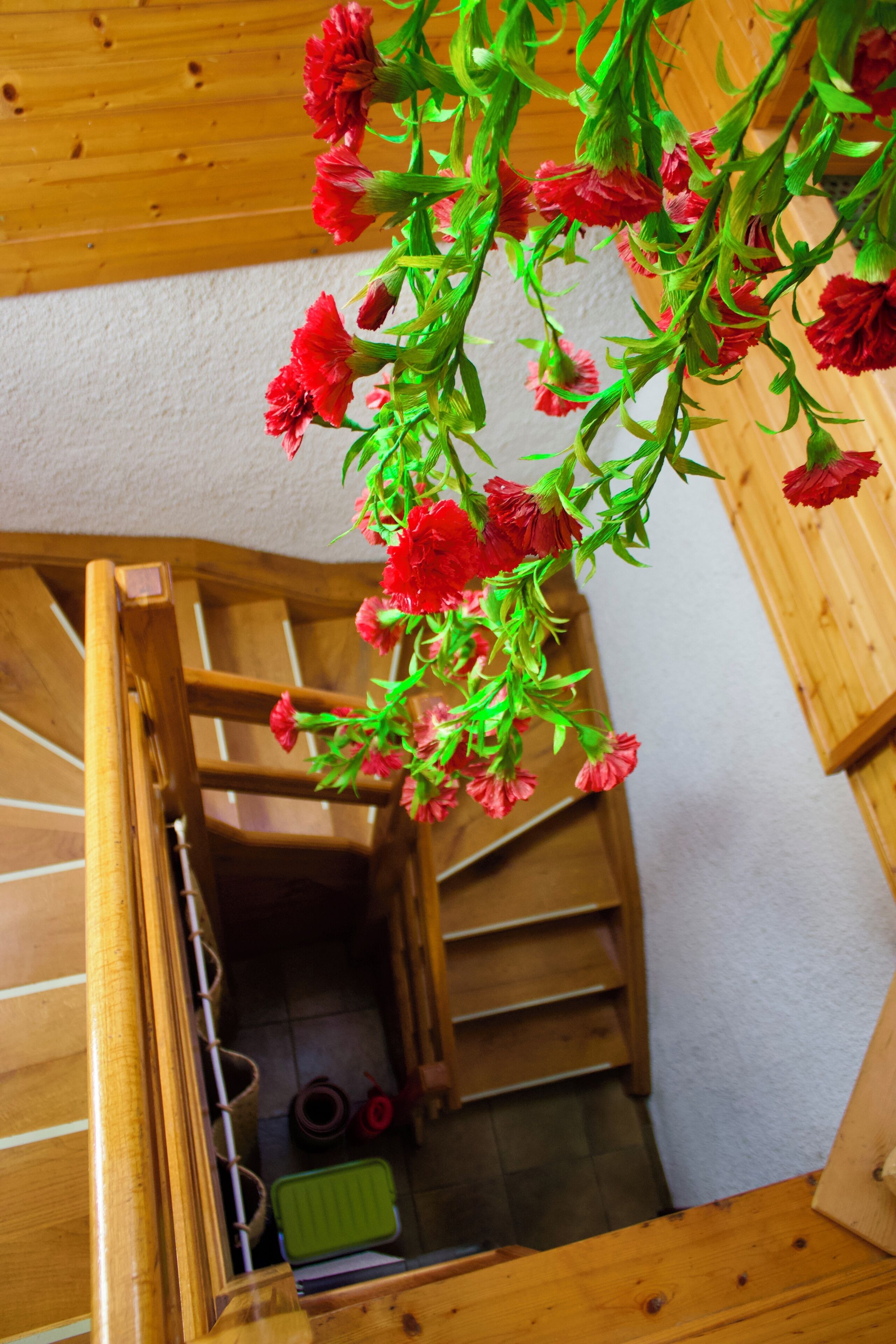 A wooden staircase with a hanging red flower arrangement.