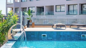 Un hôtel moderne doté d’une piscine sur le toit, de balustrades en verre et offrant une vue dégagée sur le paysage urbain.