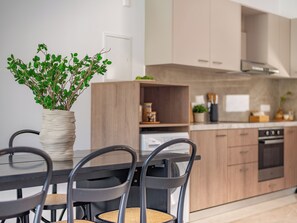 Une cuisine moderne avec des meubles en bois, une table à manger avec des chaises et une plante en pot posée sur la table.