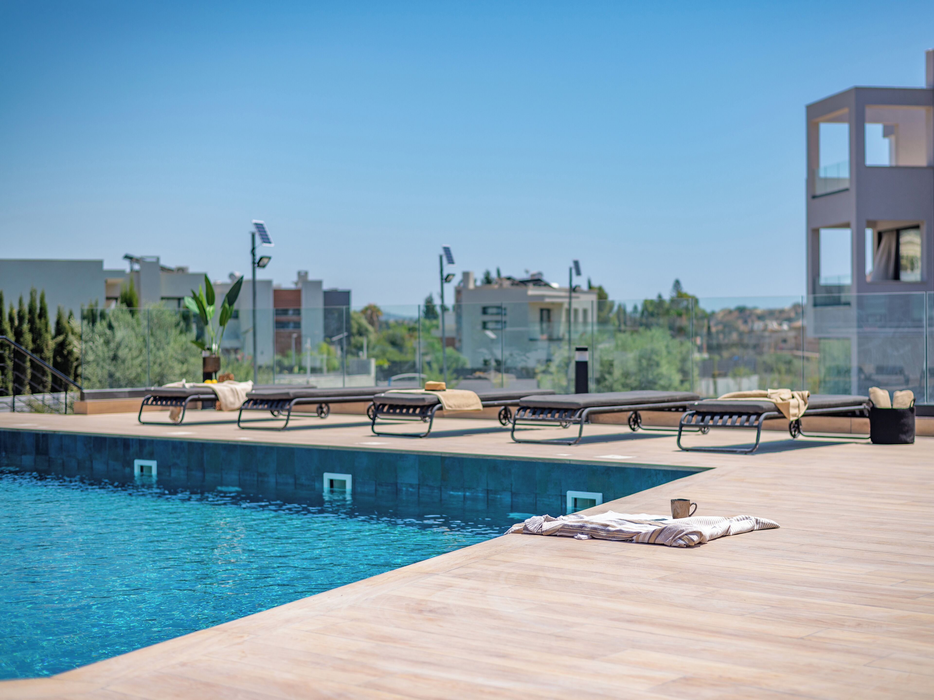 A rooftop pool area with lounge chairs and a view of the cityscape.