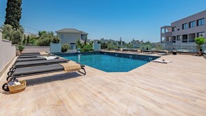 A rooftop pool with lounge chairs, a clear blue sky, and modern buildings in the background. - Sanders River Plaza - Jolly 2 Bedroom Apartment With Balcony (Limassol)