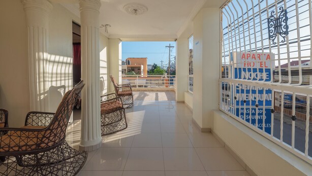 A hotel corridor with a view of the street, a balcony with chairs, and a sign advertising a discount. - Room-single Room Near SDQ Airport 300 M (Santo Domingo Este)