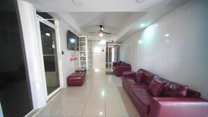 A spacious lobby with a red leather sofa, a glass door entrance, and a ceiling fan. - Room-single Room Near SDQ Airport 300 M (Santo Domingo Este)