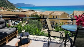 Uma varanda com vista para o mar, uma mesa e um sofá.