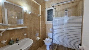 Casa de banho com lavatório, sanita e chuveiro.