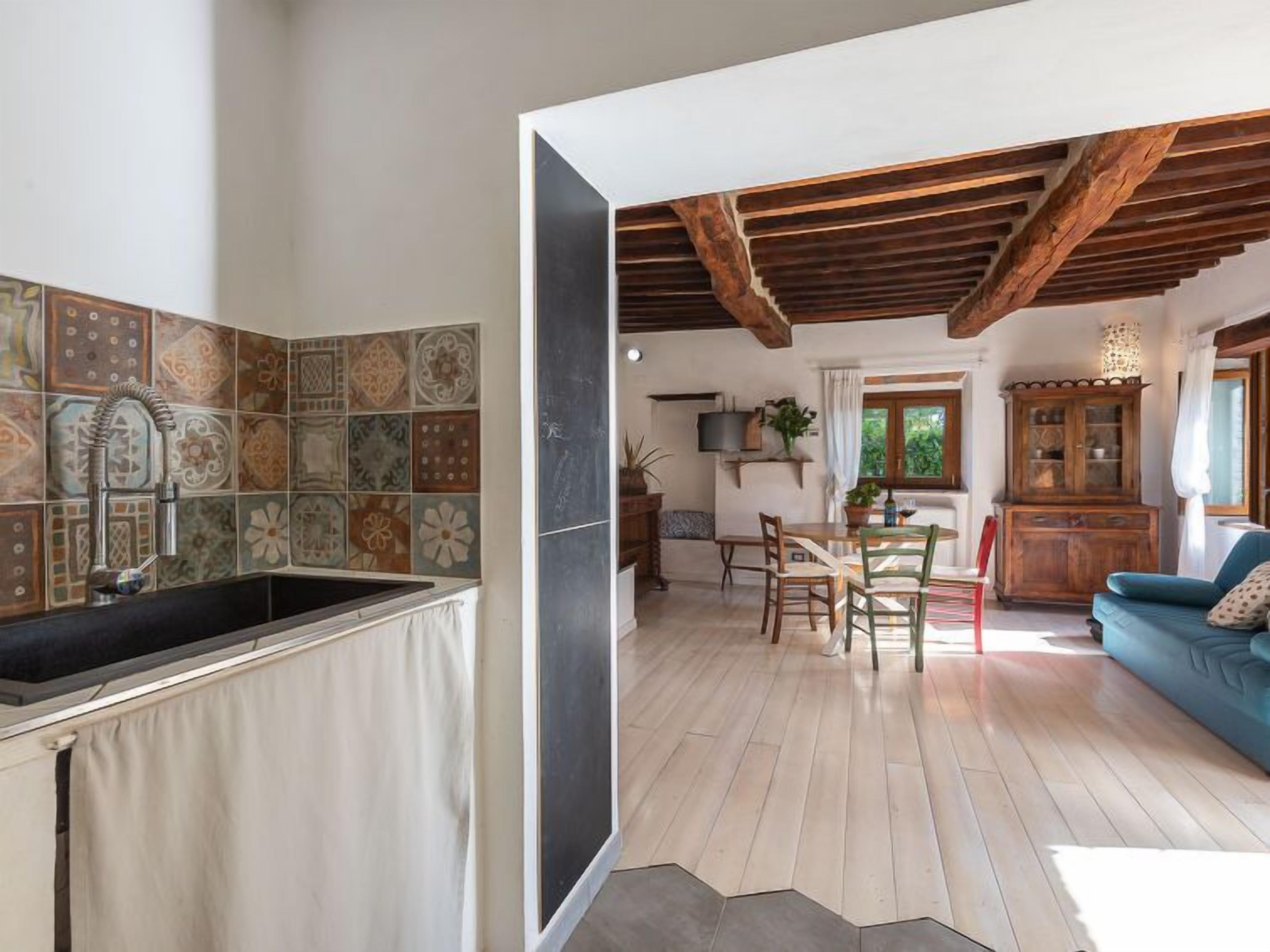 A kitchen with a tiled backsplash and a dining area with wooden furniture.