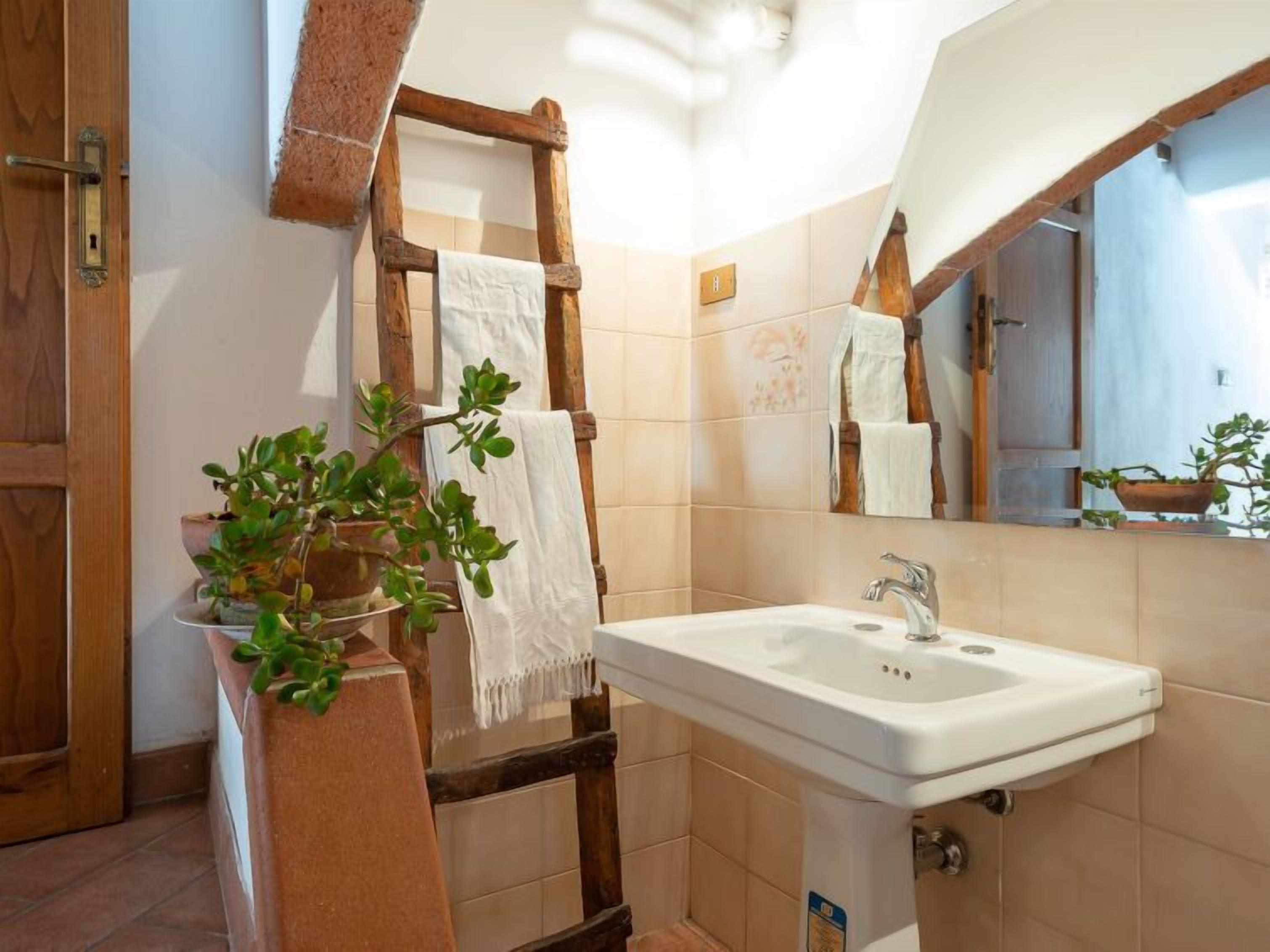 Une salle de bain avec une échelle en bois, un lavabo et un miroir.