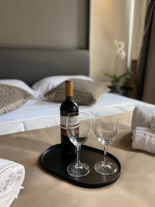 A bed with white linens, a bottle of wine, two empty wine glasses, and a tray on a table. - Soha Piazza di Spagna Boutique (Rome)