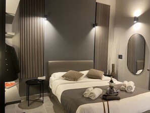 A modern hotel room with a large bed, a small side table, a mirror, and a vase with branches. - Soha Piazza di Spagna Boutique (Rome)