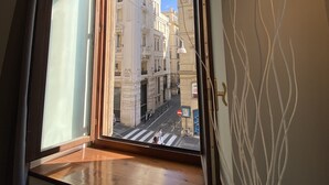Una habitación con un ventanal grande con vistas a una calle con edificios históricos.