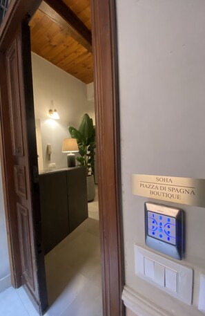 A hallway with a wooden ceiling, a sign reading "SOHA PLAZA DI SPAGNA BOUTIQUE", and a keypad lock. - Soha Piazza di Spagna Boutique (Rome)