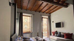 Un dormitorio con cama, sofá, televisión y ventana con cortinas.