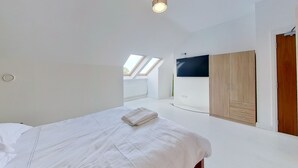 Une chambre à coucher avec un lit, une armoire et des fenêtres de toit.
