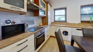 Une cuisine compacte équipée d’un four à micro-ondes, d’un four traditionnel et d’un lave-linge.