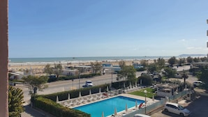 A pool area with lounge chairs and umbrellas, a clear view of the beach, and a parking lot. - AmaRèmin - LIVING RIMINI - Modern apartment overlooking the sea (Rimini)