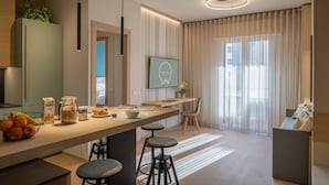 A modern kitchen with a central island, bar stools, and a dining area with a chair. - AmaRèmin - LIVING RIMINI - Modern apartment overlooking the sea (Rimini)