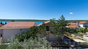 Un área residencial costera con tejados de tejas de color terracota, un cielo azul despejado y vista al mar.