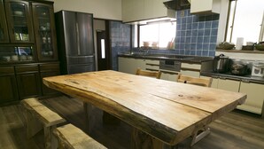 Eine Küche mit Holztisch, Bänken, einem Kühlschrank, einem Herd und einer blau gefliesten Spritzwand.