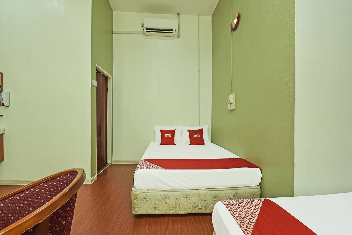 A hotel room with a bed, a desk, and a door.