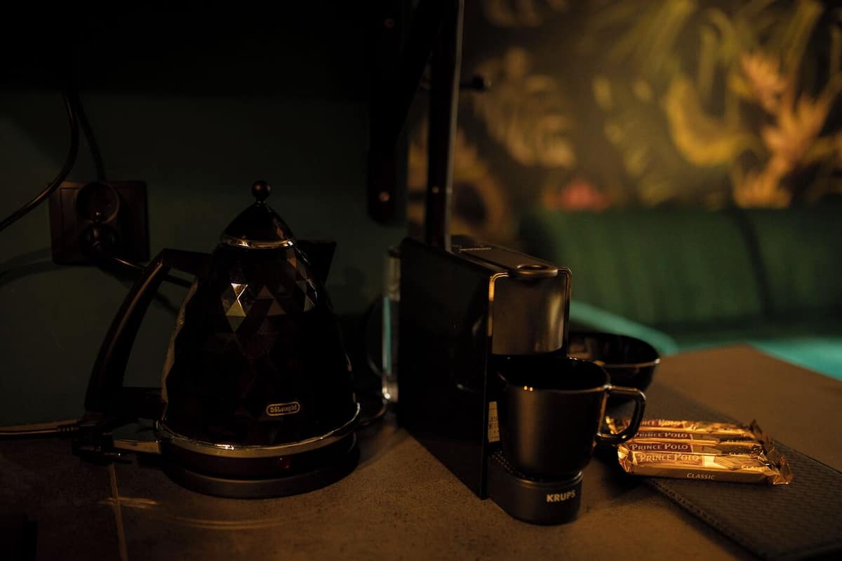 Una cafetera, una taza y un paquete de café Prince Polo Classic sobre una mesa.