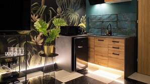 A modern kitchen with a checkered floor, a wall-mounted TV, a sink, and wooden cabinets. - Jungle Apartments (Wroclaw)