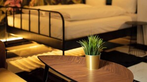 A bedroom with a bed, a nightstand, a small table with a plant, and a wall mural. - Jungle Apartments (Wroclaw)