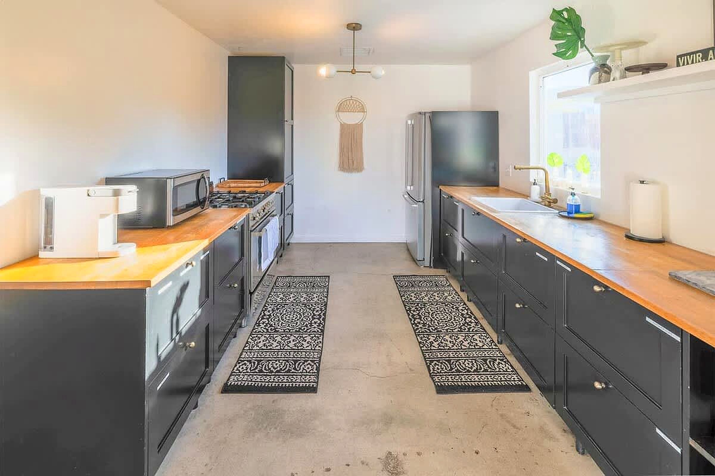 A modern kitchen with black cabinets, a wooden countertop, a stove, and a refrigerator.