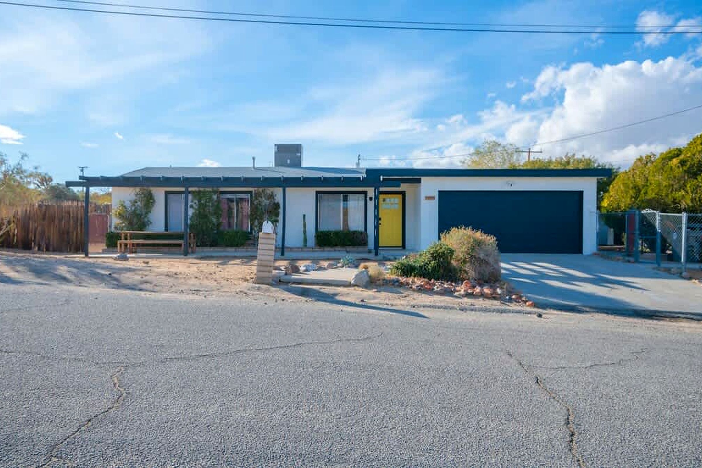A single-story building with a garage, a covered porch, and a small garden area.