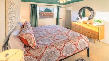 A bedroom with a bed, a dresser, a mirror, and a ceiling fan.