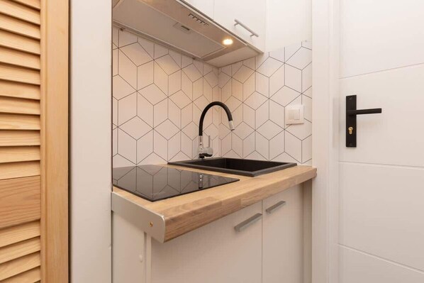 A kitchen with a black faucet, a wooden countertop, and a hexagonal tile backsplash.