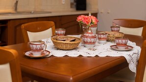 Una mesa de comedor decorada con tazas estampadas, una cesta de pan y un florero con flores.