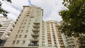 Un edificio residencial de varios pisos con balcones, entrada a nivel de calle y una señal visible.